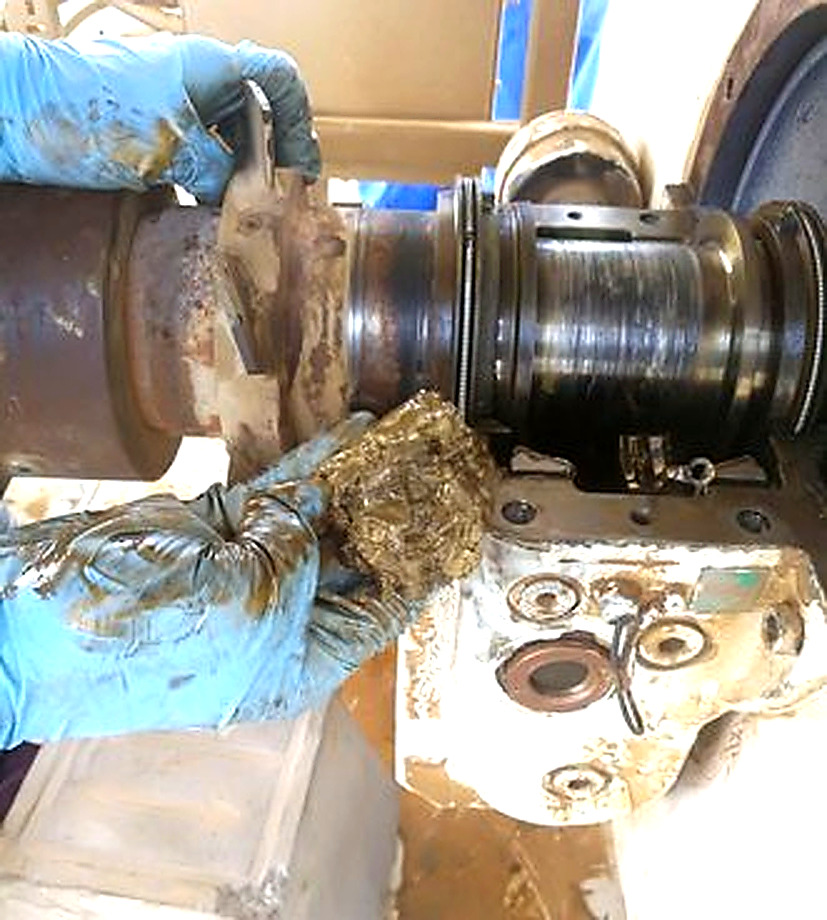Oil ring broken into two separate halves laid flat, showing fatigue fracture and uneven wear from unstable rotation in degraded lubricant conditions